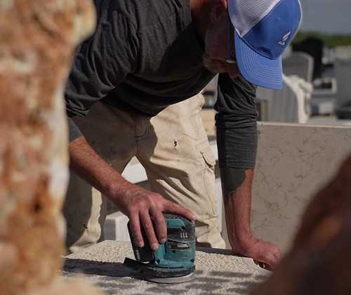 A Tending specialist cleaning a granite headstone